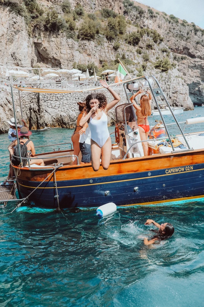 Women swimming beside a boat on the Amalfi Coast